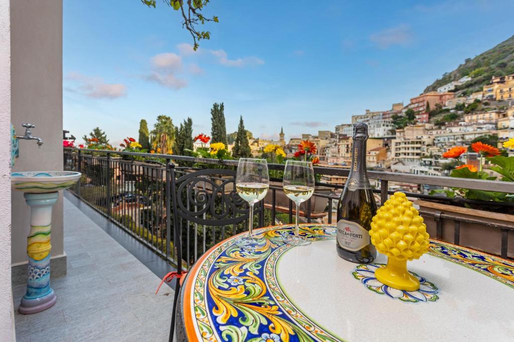 a table with two glasses of wine on a balcony at Tao Rama Suite in Taormina