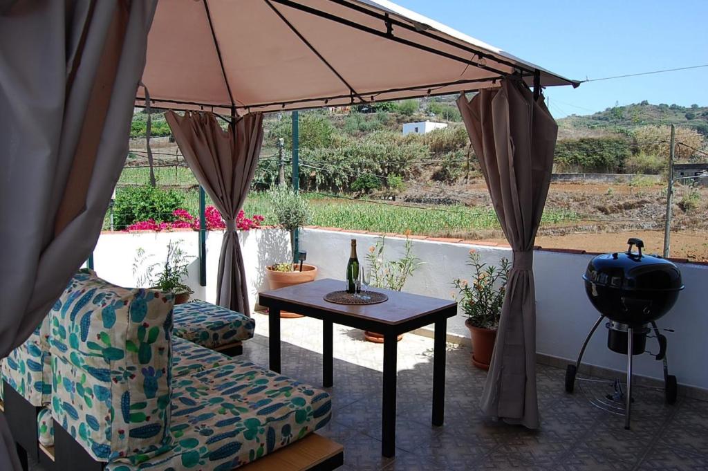 a patio with a table and a chair and an umbrella at Las Monarcas in Teror