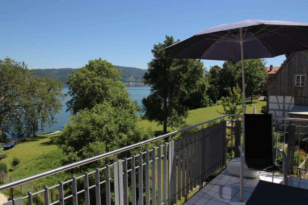 a balcony with an umbrella and a view of the water at Ferienwohnung Ledergerber in Bodman-Ludwigshafen
