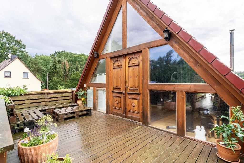 a wooden house with a large glass door on a deck at Wohlfühlurlaub in der Scheune in Ochsensaal