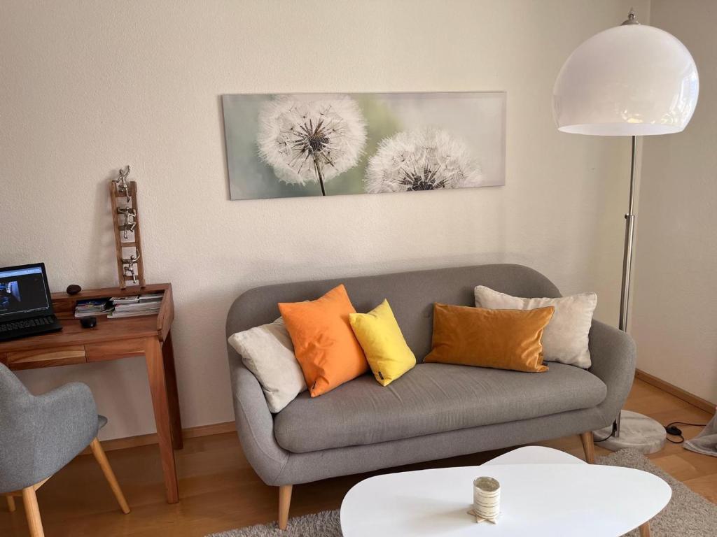a living room with a gray couch with orange pillows at Lichtdurchflutete Wohnung in Kempten
