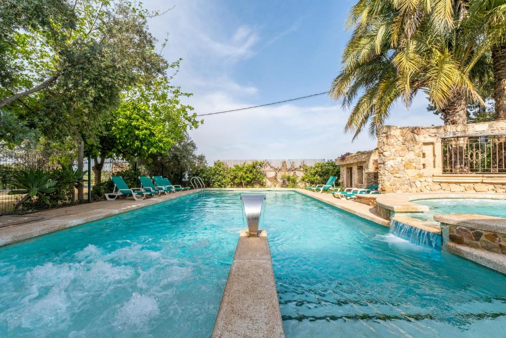 a pool with blue chairs and a palm tree at La Carrasca - Naranja in Catral