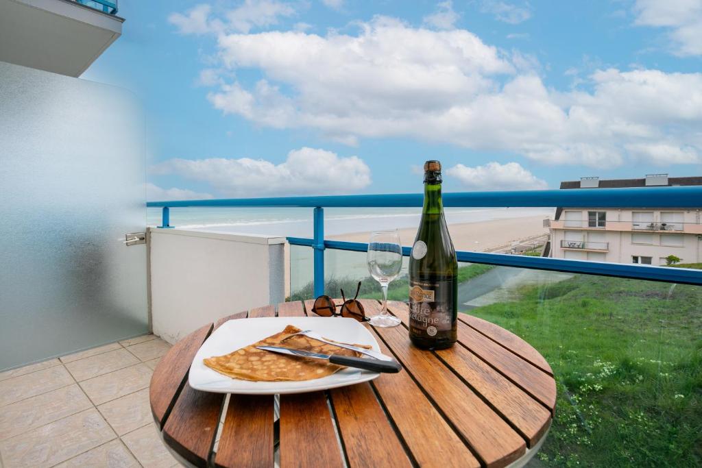 a table with a bottle of wine and a plate of pizza at Appartement en front de mer in Plérin