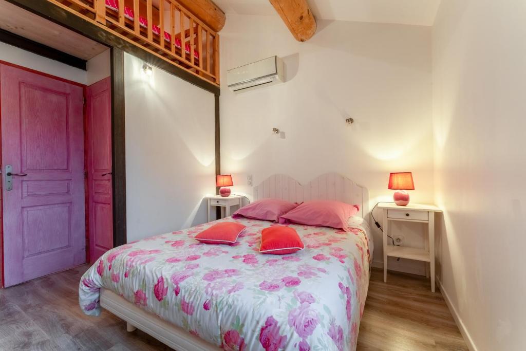 a bedroom with a bed with pink pillows on it at Chambre Laurier Rose in Piolenc