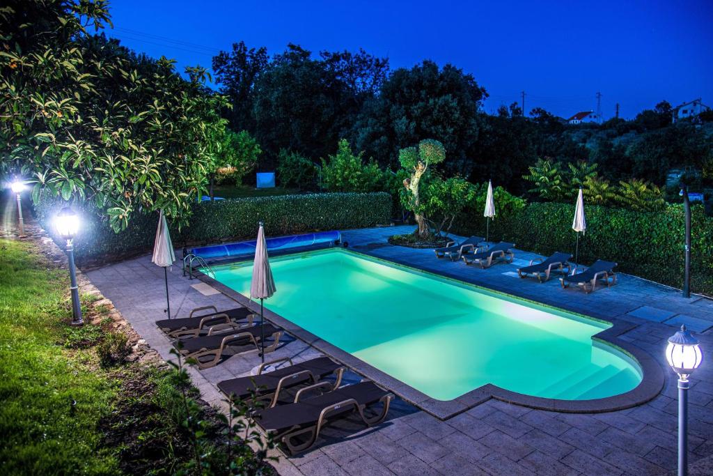 a swimming pool with chairs and umbrellas at night at Recanto Transmontano in Macedo de Cavaleiros