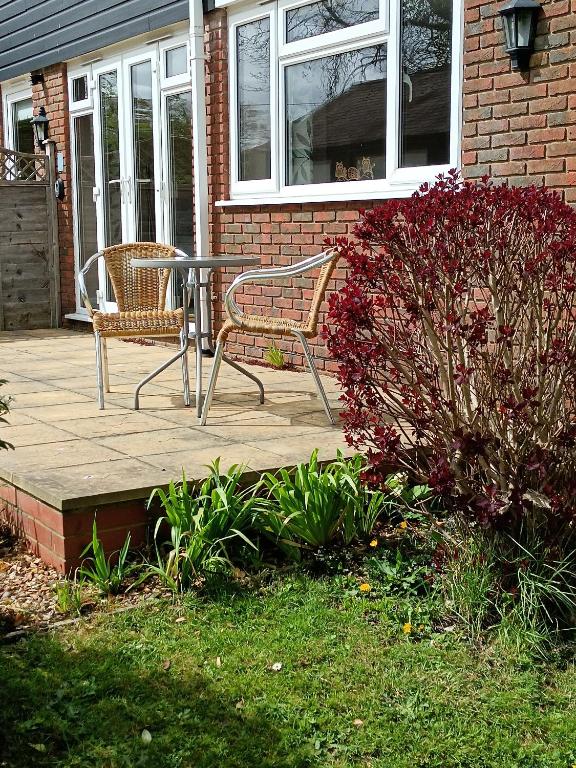 a patio with two chairs and a table in front of a house at Greenbanks 2 Damerham Self Catering in Damerham