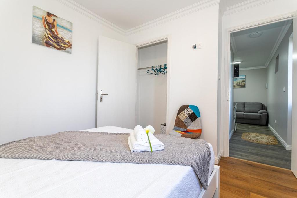 a white bedroom with a bed and a chair at Oásis Fonte Grande in Santo António