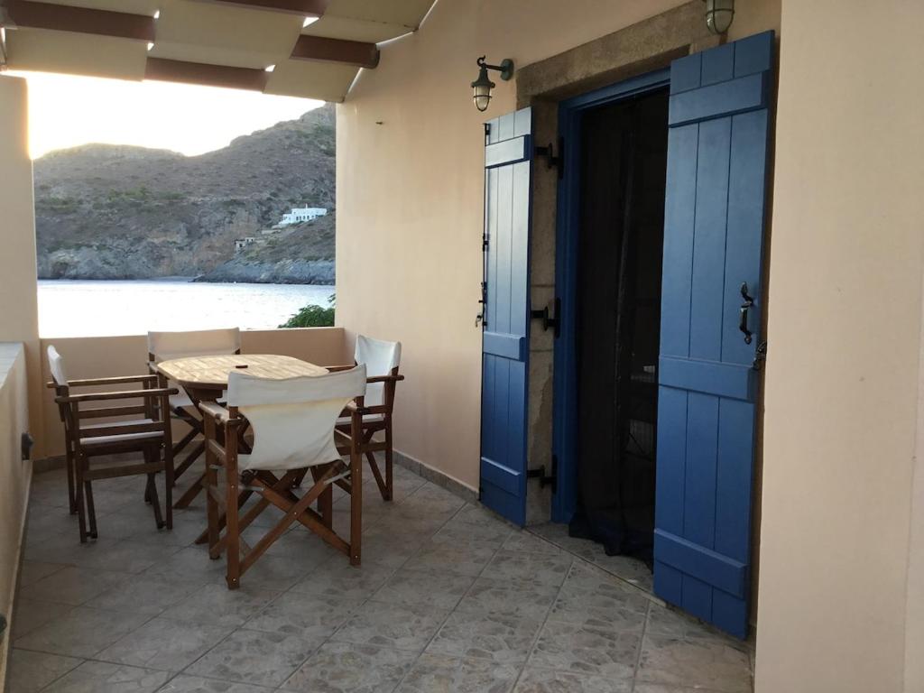 a dining room with blue doors and a table and chairs at Emma's maisonette house by Kapsali beach in Kapsali