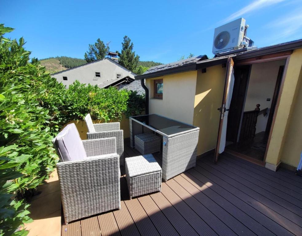 a deck with four wicker chairs and a table at El Camino in Molinaseca