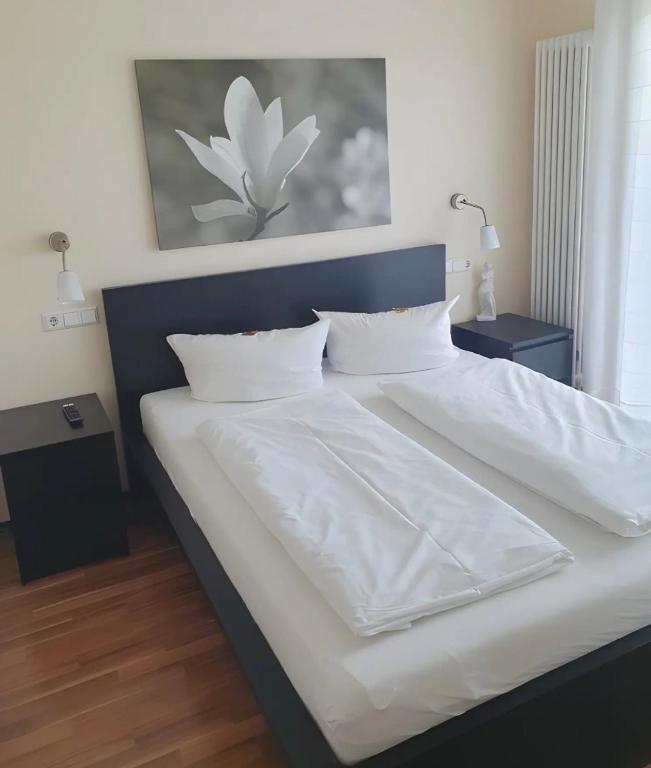 a large bed with white sheets and pillows at Hotel Sonnenhof in Illertissen