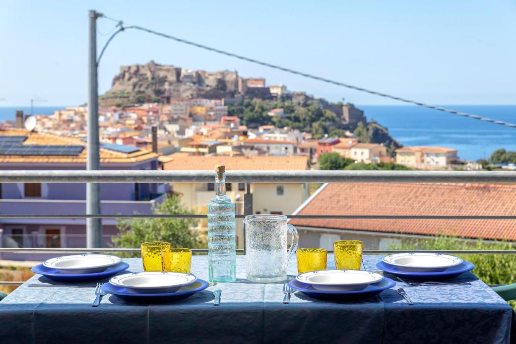 a table with plates and glasses on top of a balcony at Ad occhi aperti - Castelsardo in Castelsardo