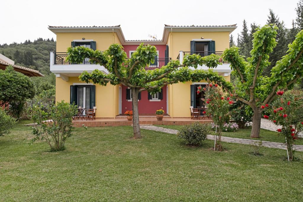 a yellow and red house with trees in the yard at Villa Rita in Spanokhórion