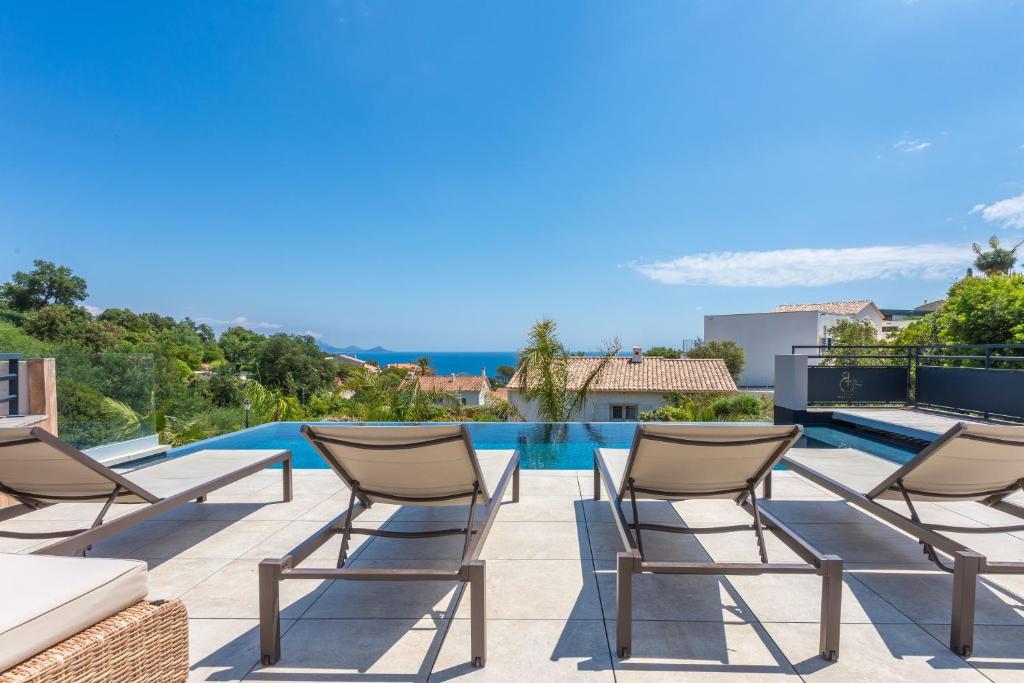 a patio with chairs and a swimming pool at Villa Belenos Piscine vue mer in Roquebrune-sur-Argens