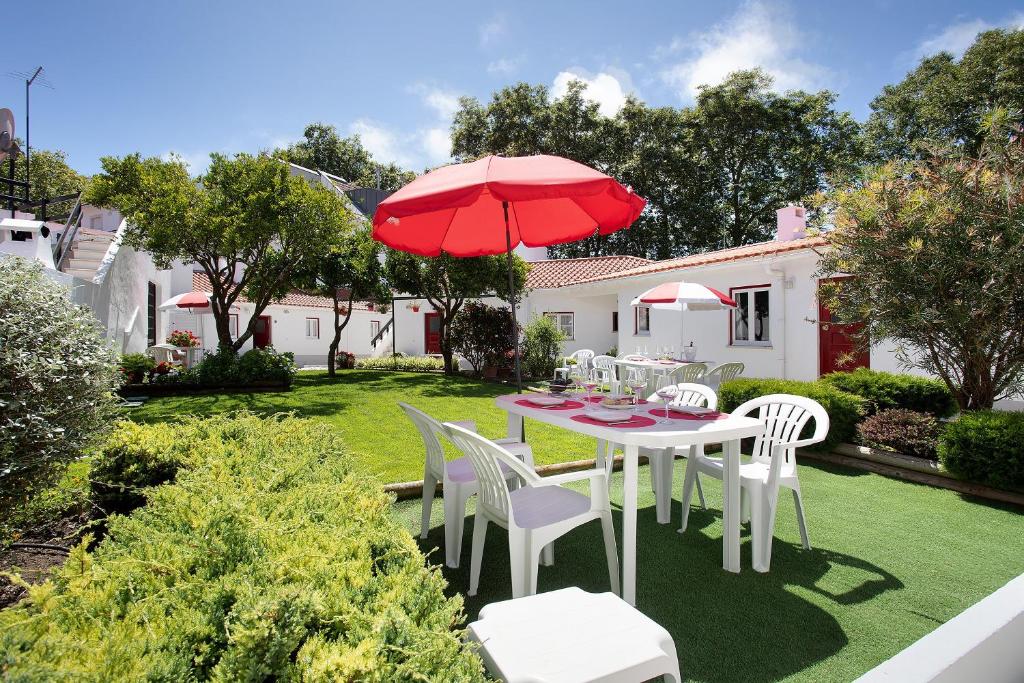 a table and chairs with a red umbrella in a yard at Páteo da Várzea 4 in Colares
