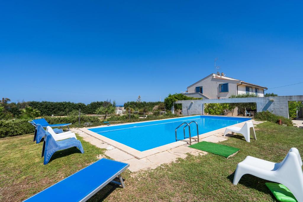 a swimming pool with blue tables and chairs in a yard at Melus Maris in Syracuse