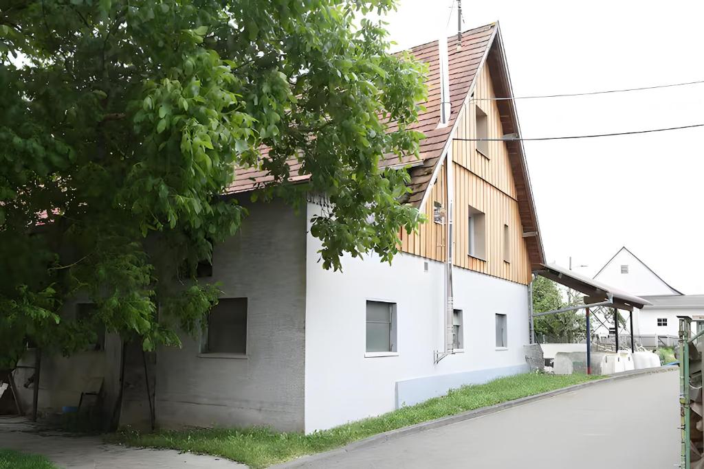 a white building with a wooden roof at Ferienwohnungen beim Weilerbauer in Gerstetten