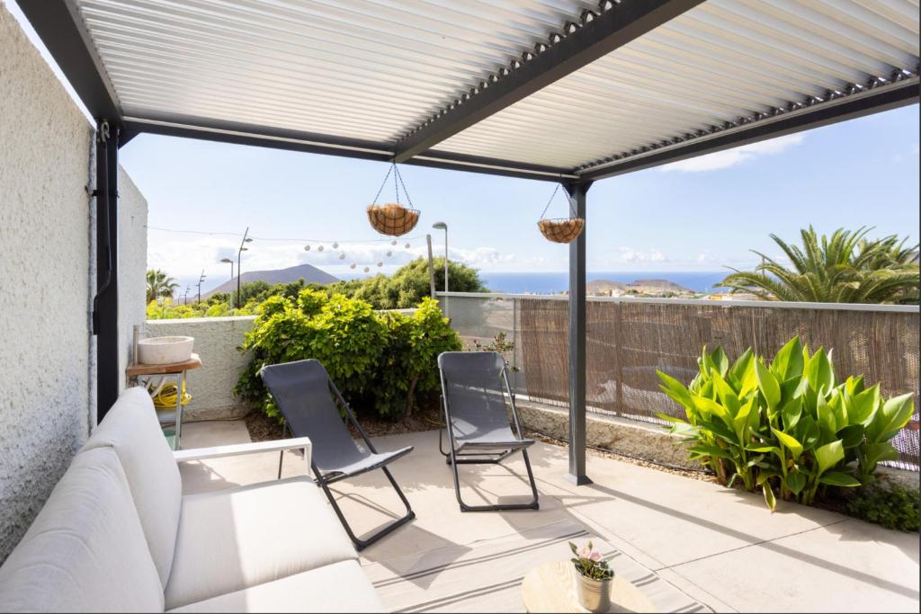 a patio with a white pergola and chairs at Villa en Taro in Güimar