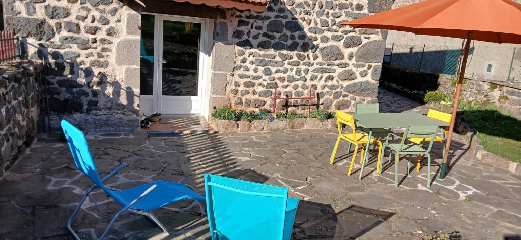 a patio with a table and chairs and an umbrella at Maison de campagne in Séneujols