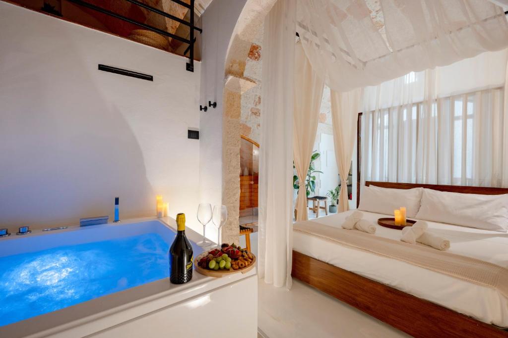 a bedroom with a tub and a bed with a bottle of wine at Archè Luxury private Spa in Polignano a Mare