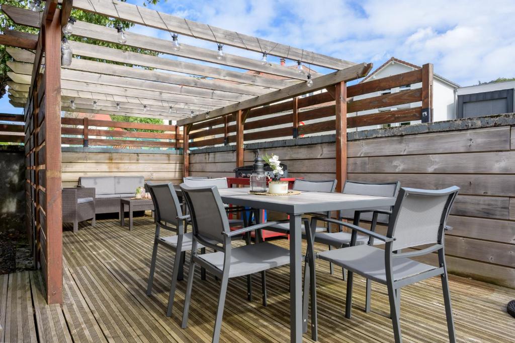 a patio with a table and chairs on a deck at La Petite Chaumière avec sauna in Saint-Maurice-sur-Moselle