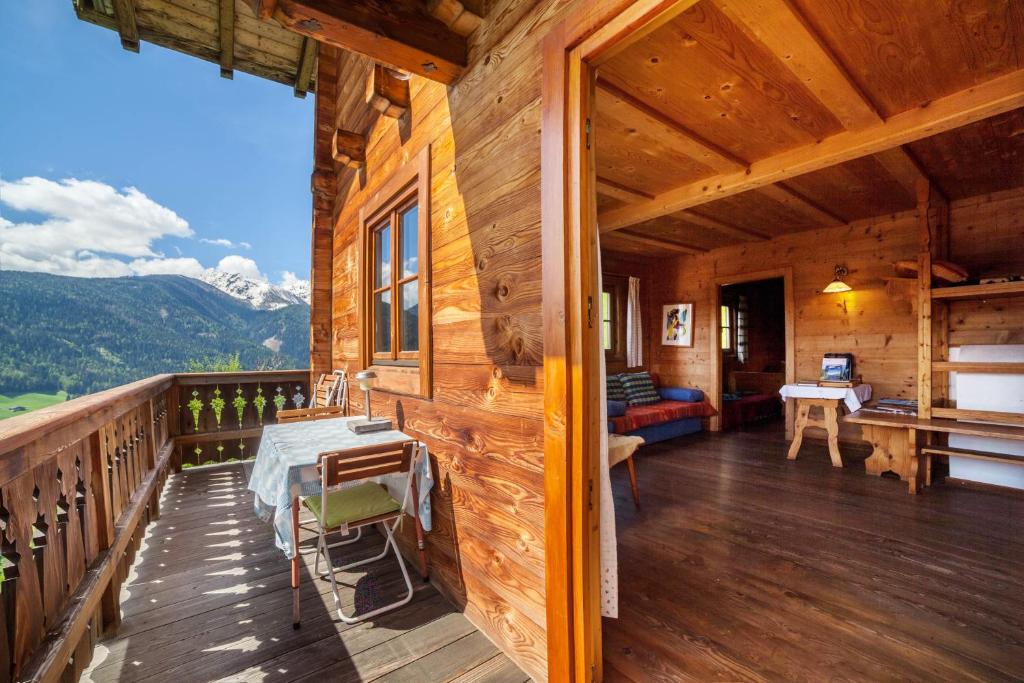 a porch of a wooden cabin with a table and a desk at Ferienhaus Rauchegg - Seeblick in San Pancrazio dʼUltimo