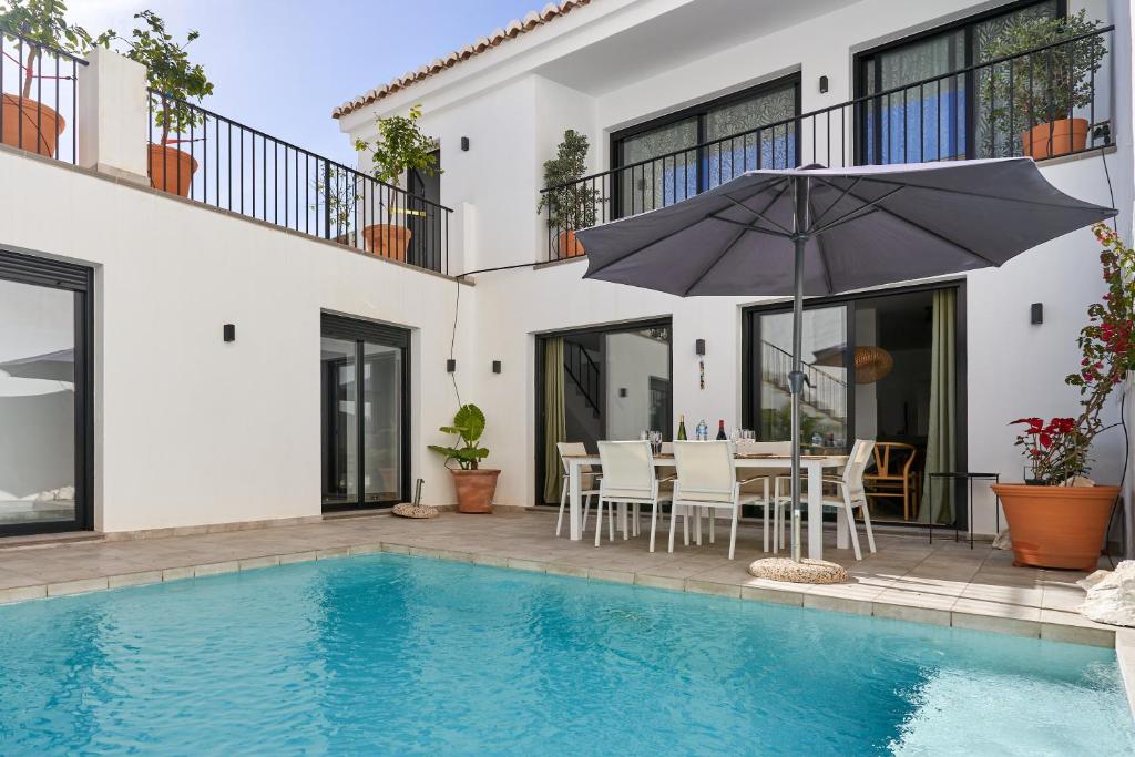 a villa with a swimming pool and a table with an umbrella at El Cine in Canillas de Albaida