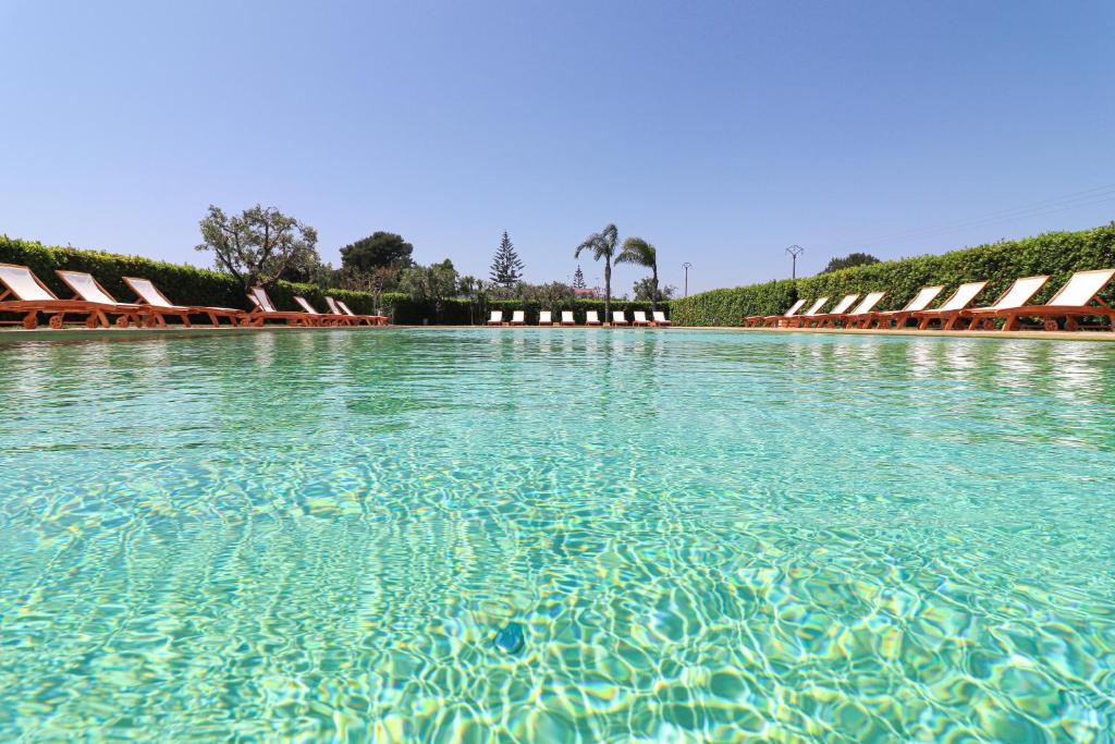 a large pool of clear blue water with lounge chairs at Bungalow Pizzutella in Otranto