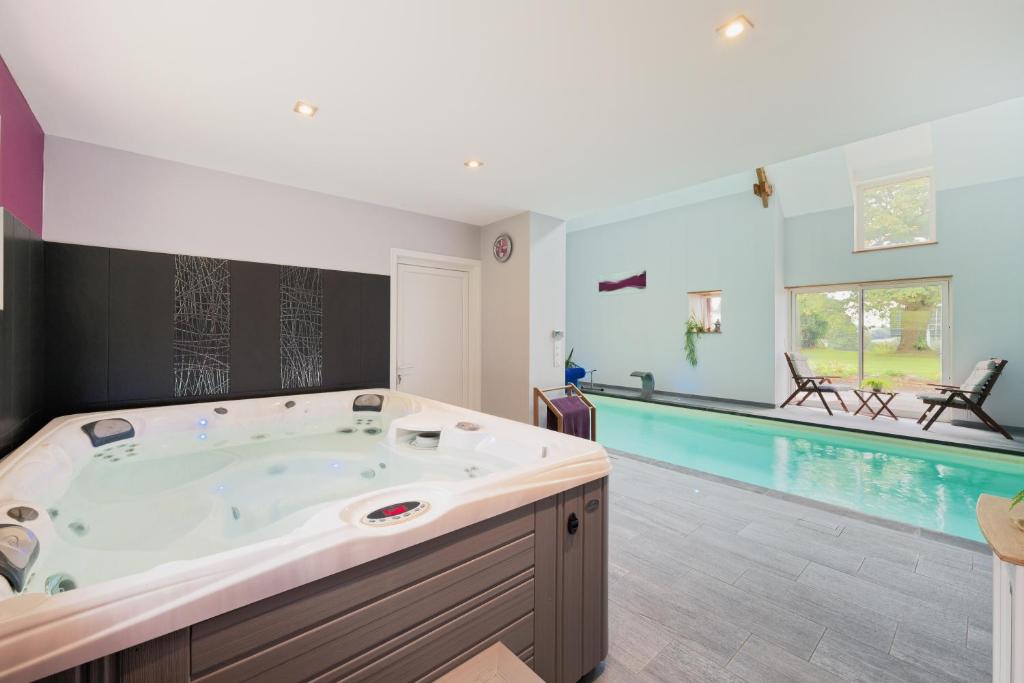 a large bathroom with a tub and a swimming pool at Gîte La Clémençaie in Réminiac