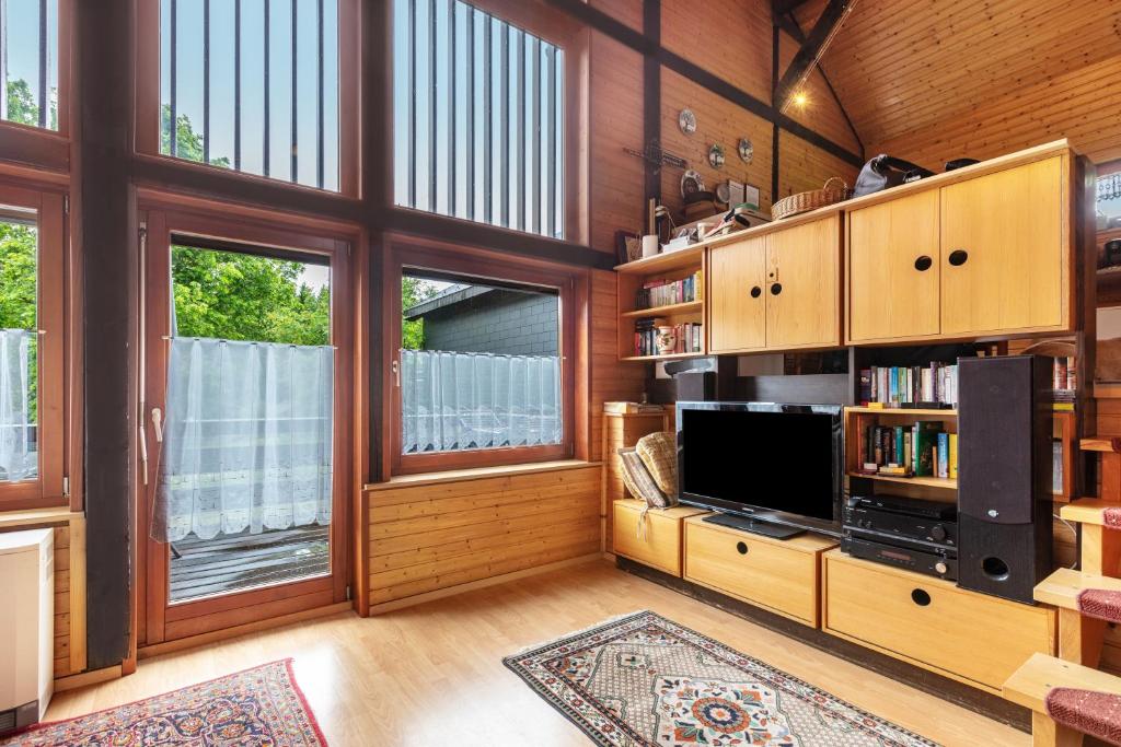 a living room with a tv and some windows at Feriendorf Rechbergblick, Haus 29 in Bernau im Schwarzwald