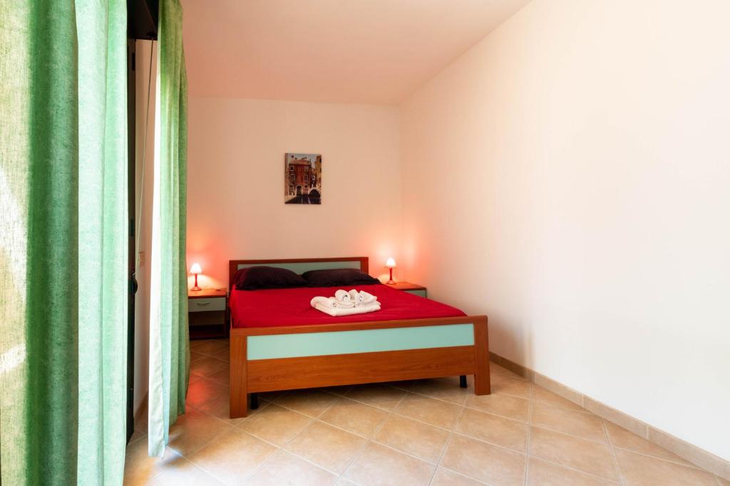 a bedroom with a red bed with two candles on it at Appartamenti Cavour Codice E in Villasimius