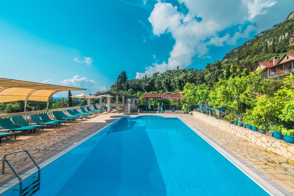 a swimming pool with chairs and mountains in the background at Andromaches sea view studio 2 in Corfu