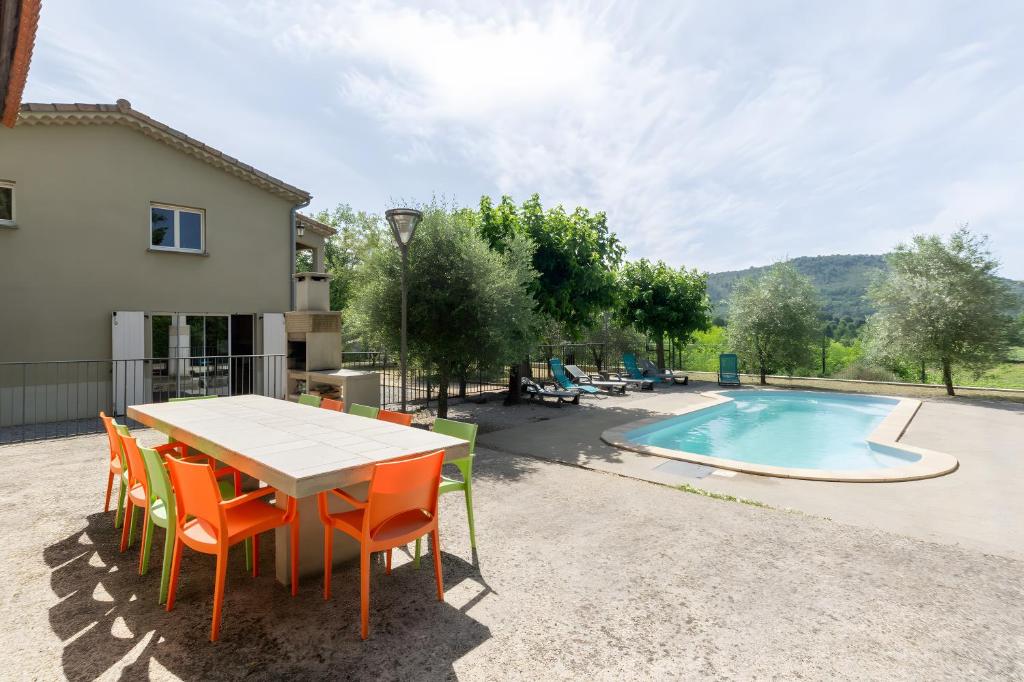 a patio with a table and chairs next to a swimming pool at Le Serre Du Puech in Chambonas
