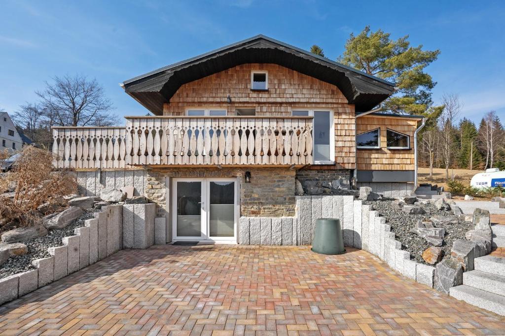 a brick house with a balcony on a brick driveway at Ferienhaus Fenzl in Johanngeorgenstadt