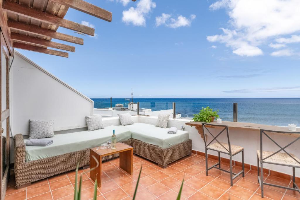 a patio with a couch and chairs and the ocean at Casa Roque in Haría