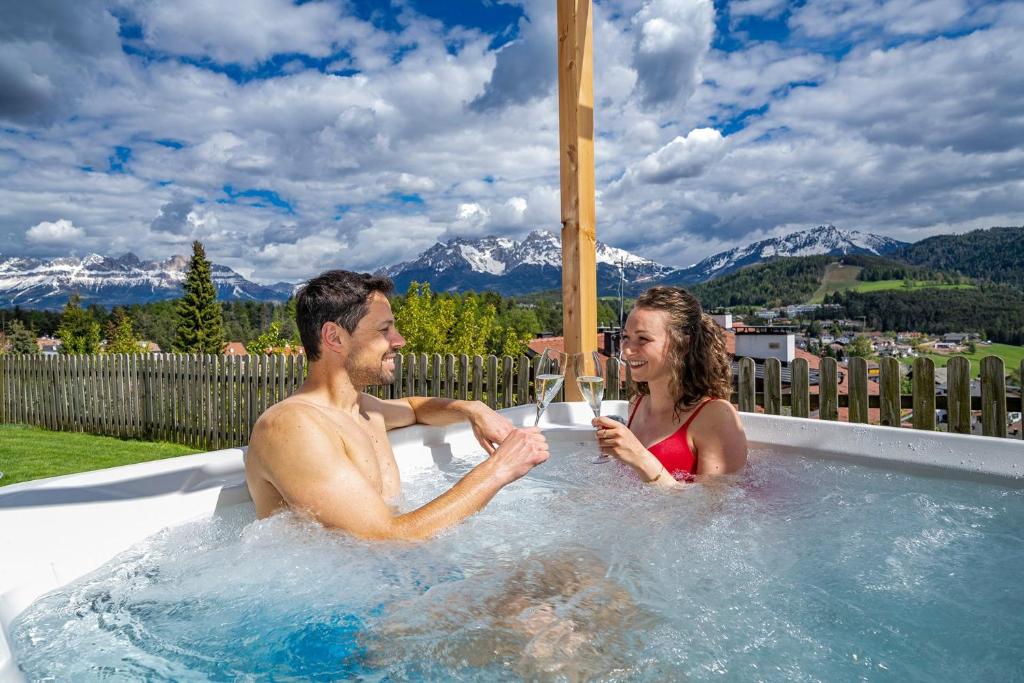a man and a woman sitting in a hot tub at Chalet Schlossberg Rosengarten in Nova Ponente