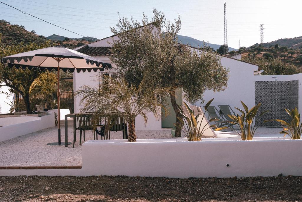 a white house with a table and an umbrella at Villa Bellido in Alora