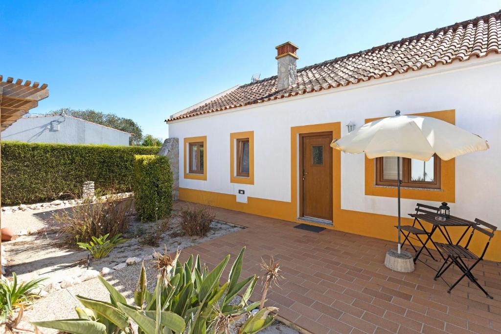 a patio with an umbrella and a house at Monte do Tanoeiro - Casa da Barrica in Rogil