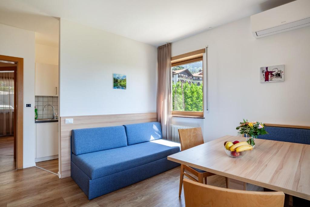 a living room with a blue couch and a table at Gartenheim App Leonhard in Schenna