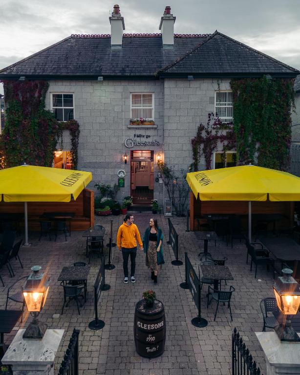 two people walking in front of a restaurant with yellow umbrellas at Gleeson's Roscommon in Roscommon