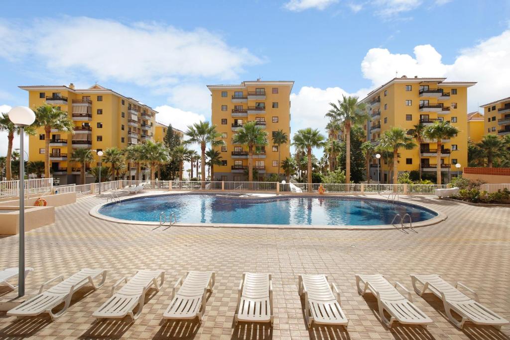 a pool with lounge chairs in front of some buildings at Casa Roberto in Candelaria