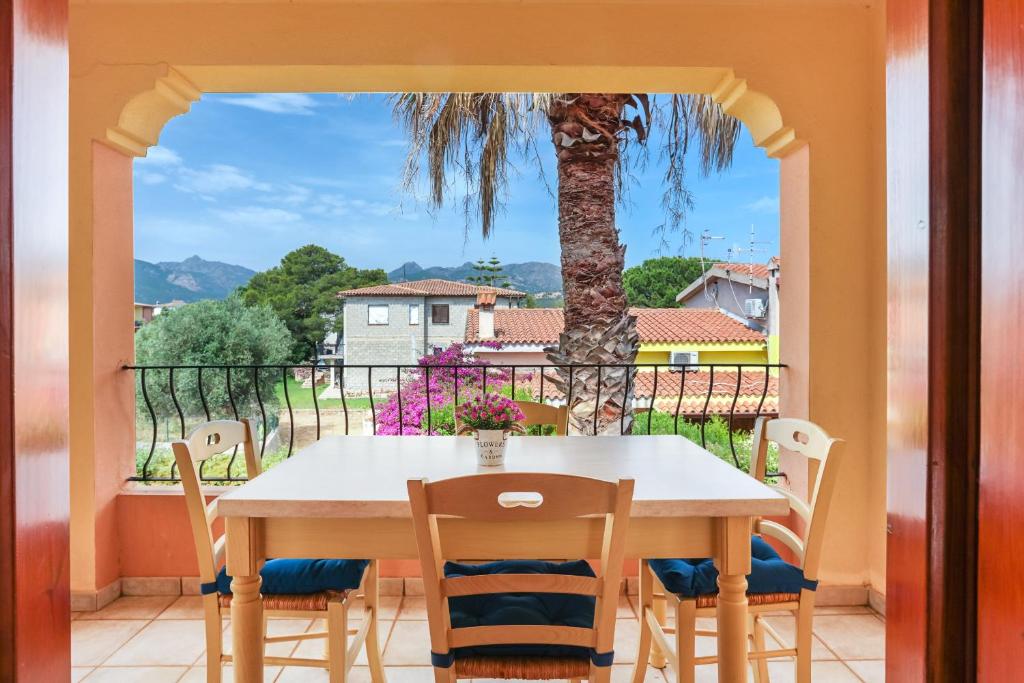 a table and chairs on a balcony with a palm tree at Bilocale Geranium Beach in San Teodoro