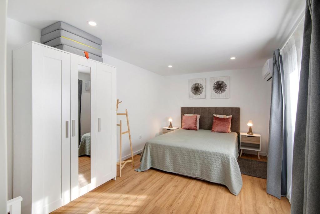 a white bedroom with a bed and a window at Telmus Villa Rc D in Monte Gordo
