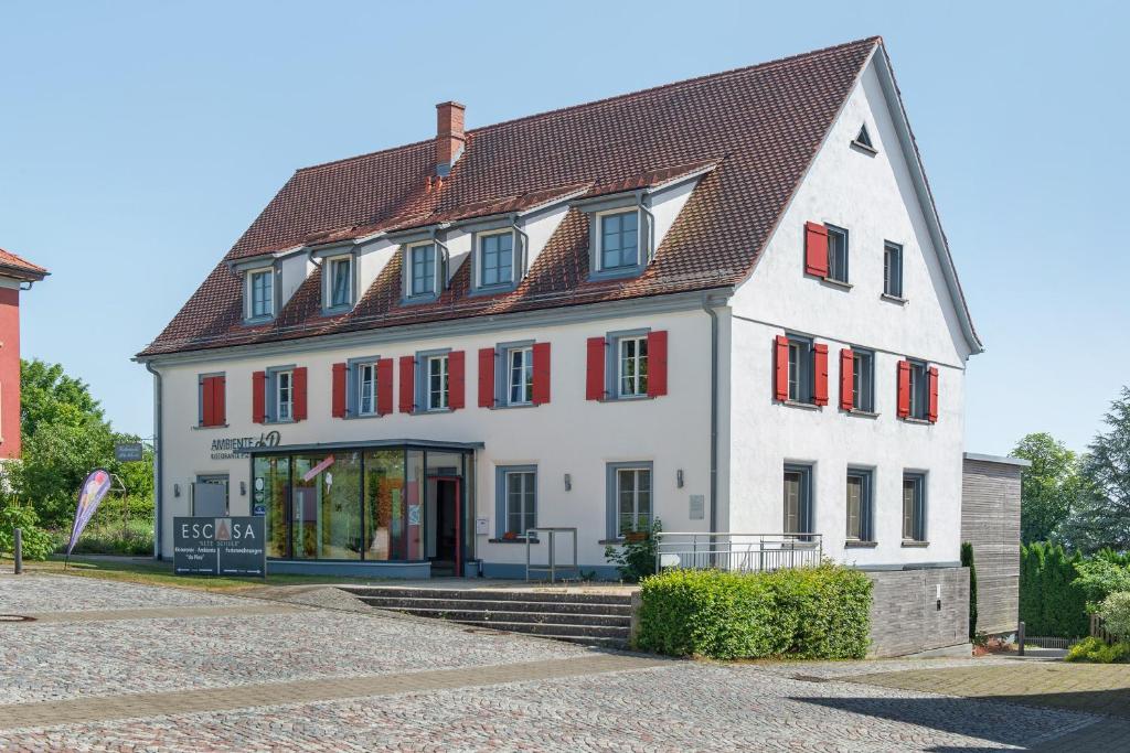 a large white building with red shuttered windows at Altes Schulhaus in Heiligenberg