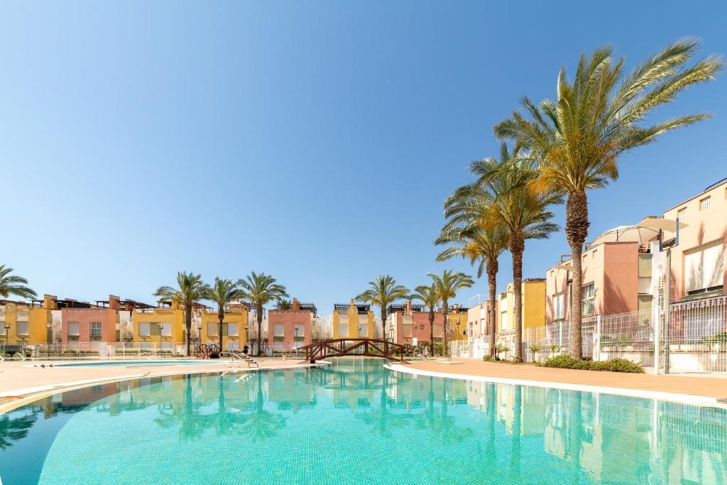 a large swimming pool with palm trees and buildings at Laguna beach Vera in Vera