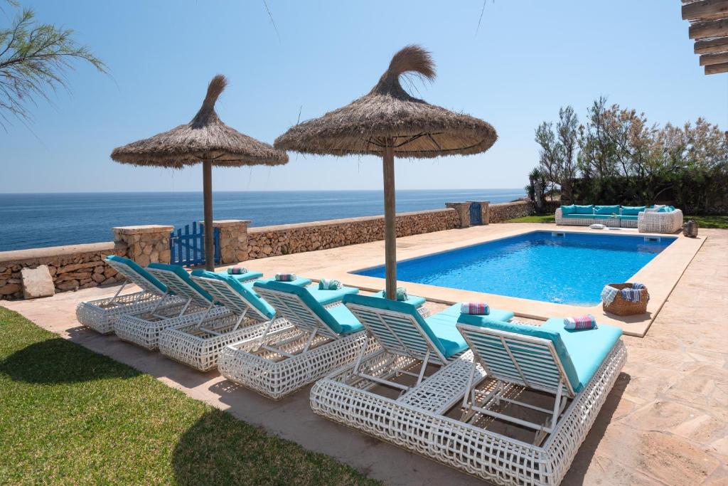 a group of chairs and umbrellas next to a swimming pool at Villa Domus Alba A - B in Felanitx