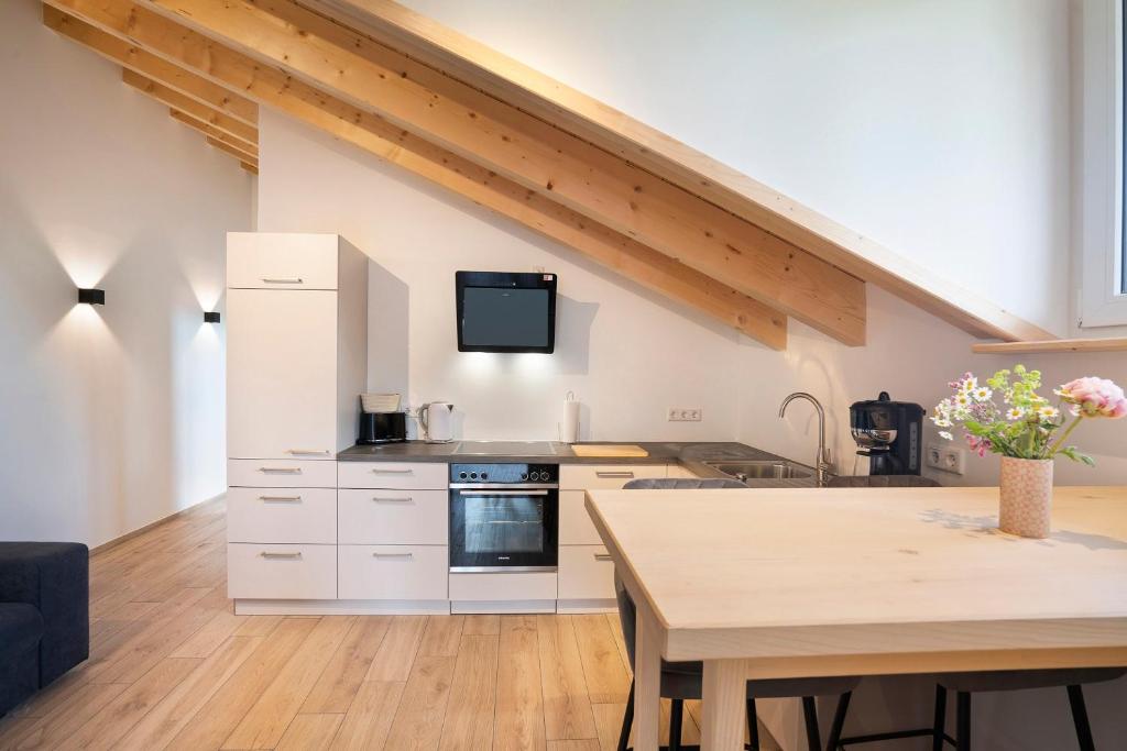 a kitchen with white cabinets and a wooden table at Ferienwohnung Wendelsteinblick in Bad Tölz