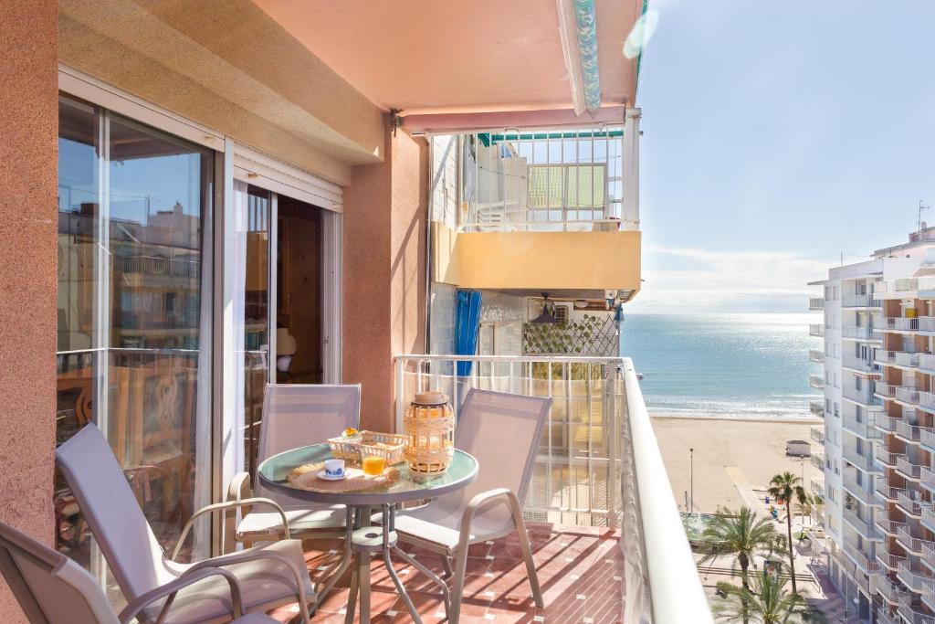 a balcony with a table and chairs and the beach at Palmera Beach House in Cullera