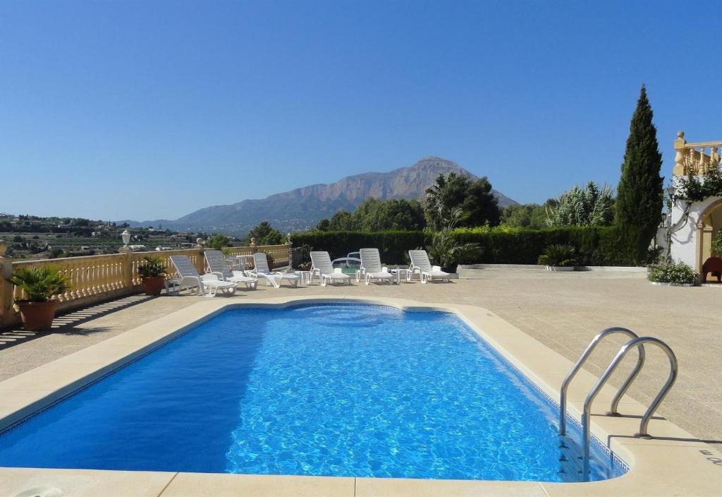 a pool with chairs and a mountain in the background at El Rafalet in Jávea