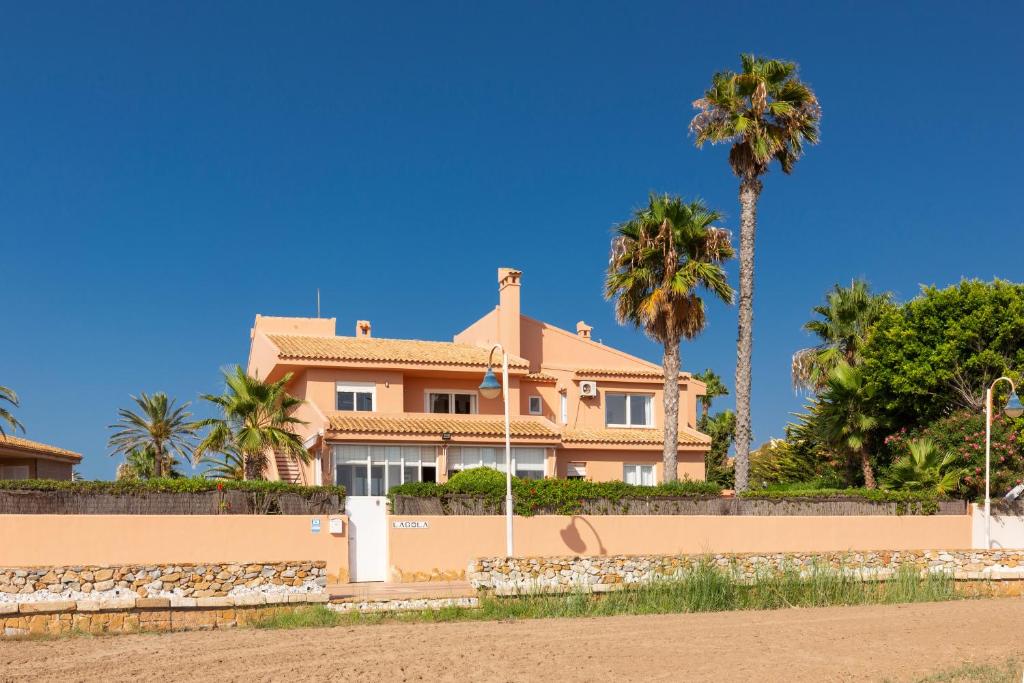 a large house with palm trees in the background at La Gola in La Manga del Mar Menor
