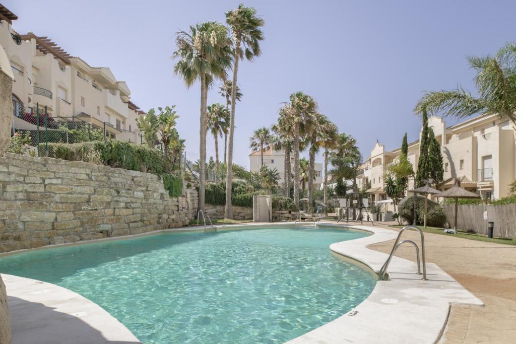 a swimming pool with palm trees and buildings at Luxury Tarifa in Tarifa